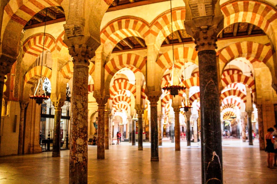 Ambient lighting highlights the red and white arches of the prayer hall of the Mezquita in Cordoba.