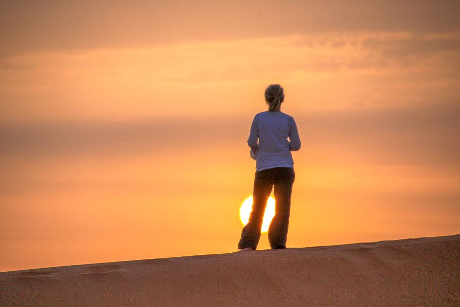 A tourist watches sunset from atop a dune in the Merzouga Desert, one of the best tours from Marrakech.