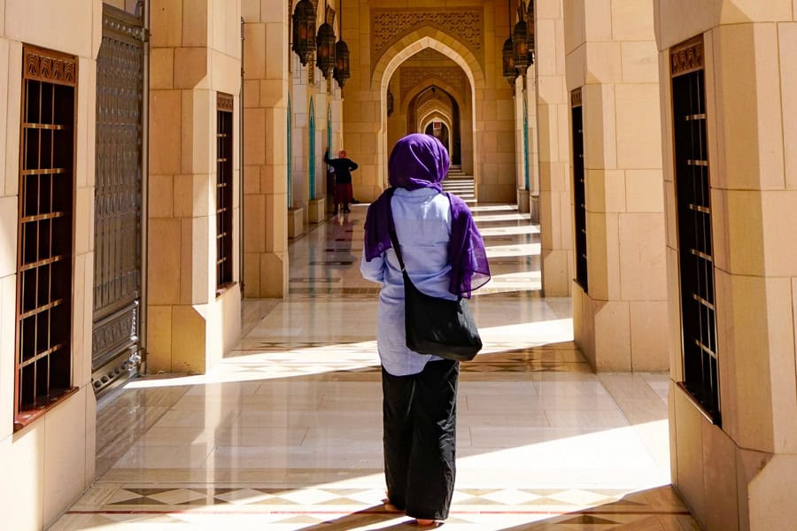 A woman veiled woman walks through a mosque in Muscat - it's always a good idea to dress modestly during your trip to Oman.