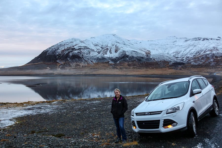 White car with winter mountain and lake backdrop - we opted for an all-wheel-drive for our 7 day itinerary for Iceland.