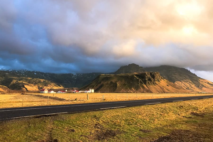 A farm with red-roofed buildings backed by mountains. 