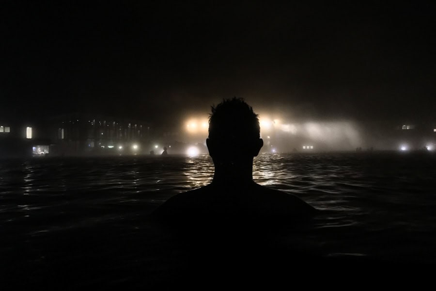 A silhouette of a person in a hot spring at night during one week in Iceland.