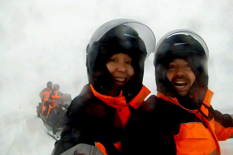 A couple enjoy a snowmobile tour on Myrdalsjökull Glacier in challenging conditions – an excursion worth adding to your one week Iceland itinerary.