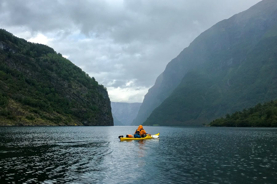 A lone kayaker paddles a rainswept Nærøyfjord, one of the most beautiful fjords in Norway.