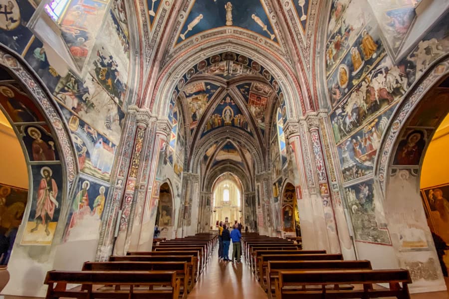 The inside of a church with benches and brightly painted walls and ceiling.