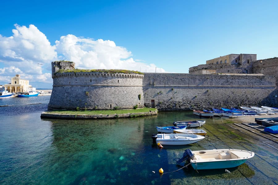 Gallipoli’s medieval fortress rises above the water with boats in the foreground.