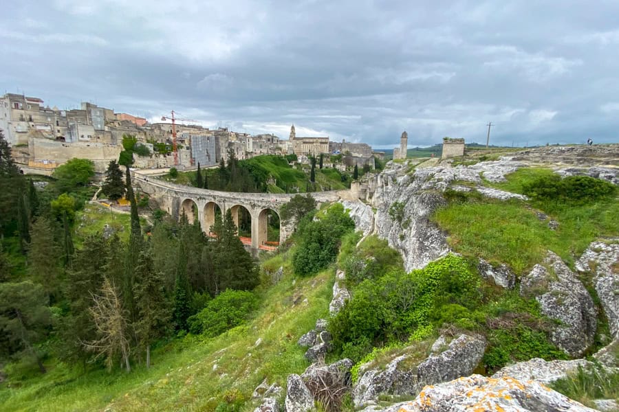 Itinerary for Puglia: An arched stone bridge crosses a ravine with buildings in the background.