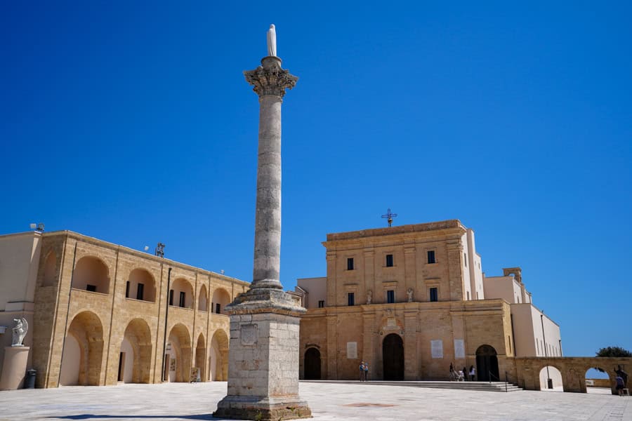 A stone pillar rises in front a square church building in Leuca.