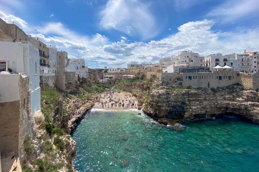 A beach tucks between cliffs topped with buildings in Polignano a Mare.