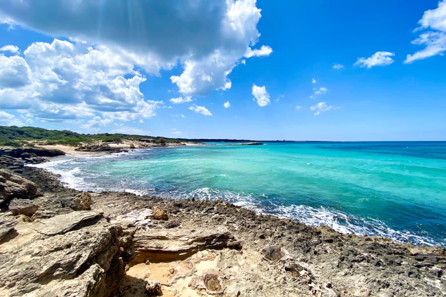 A rocky beach with blue water and clouds at Punta Suina near Gallipoli.