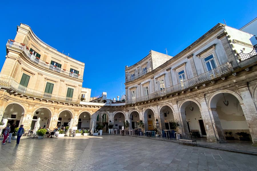 A curving wall of archways with tables in Martina Franca.