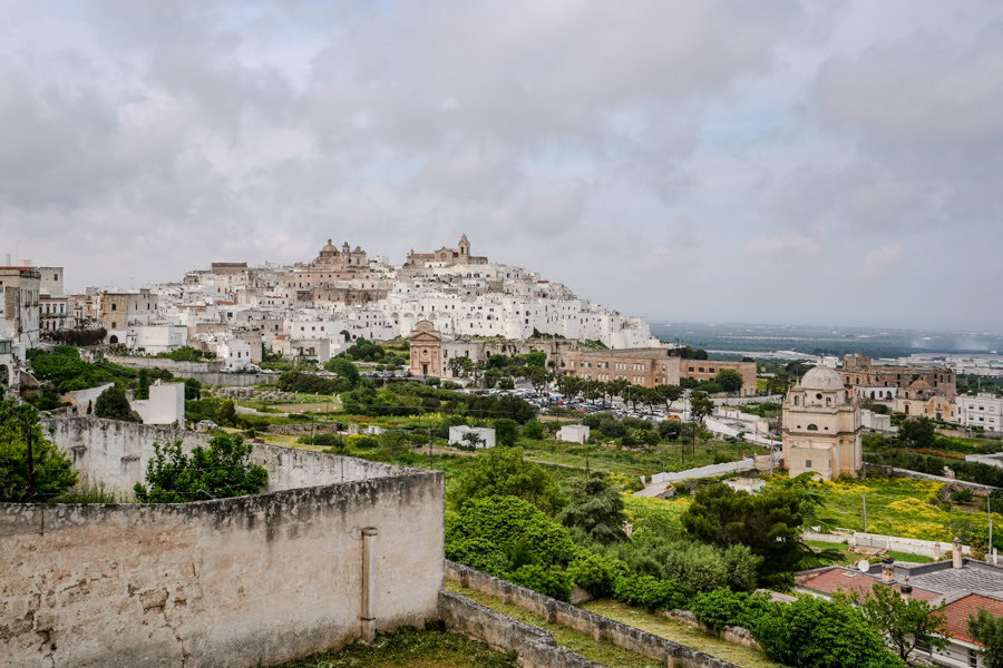 White buildings rise high above surrounding green plains at Ostuni, one of the coolest places to visit in Puglia.